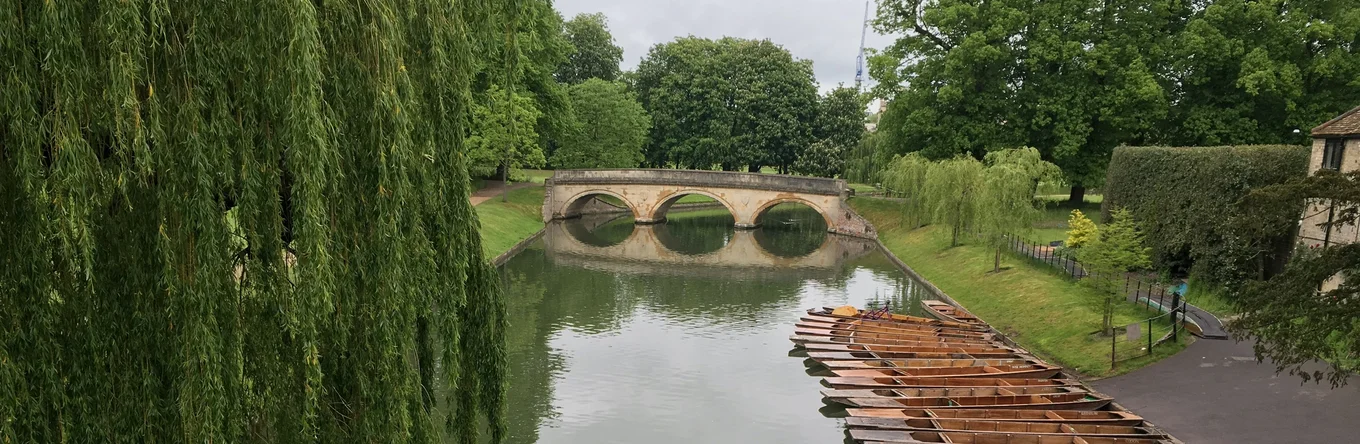 River with boats, stone bridge, and trees.